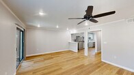 Located in Metairie, Louisiana, this 2-bedroom, 1-bathroom single-floor home offers a clean, modern aesthetic with consistent light wood flooring and neutral gray walls throughout. The open kitchen and living room area is a standout feature, with white shaker-style cabinetry, white quartz countertops, stainless steel appliances including a range, microwave, and refrigerator, and crown molding that adds a refined touch. A window over the sink brings in natural light, and the layout flows seamlessly into the living area, which features recessed lighting and a built-in shelf niche. Both bedrooms are well-sized, each equipped with a ceiling fan with light, recessed lighting, and windows that allow natural light to fill the rooms. The primary bedroom includes a sliding double-door closet, offering ample storage. The second bedroom also features a ceiling fan and a window with outdoor views. The full bathroom is finished in a crisp white palette, featuring a tub-shower combination with subway tile surround, matte black hardware and fixtures, and a white vanity with matching black hardware. A hallway connects all rooms, providing a functional and organized floor plan. The home presents a fresh, move-in-ready condition throughout.