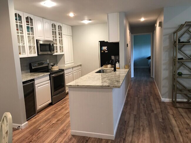 Bright white and open to the living room kitchen with granite countertops and stainless appliances - 15661 Lakeway Dr