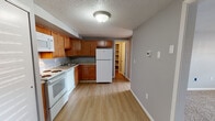 Located at 1693 Treetop Dr in Erie, Pennsylvania, this single-floor unit offers a practical and well-organized layout with neutral gray walls, light wood-look flooring in the main areas, and plush carpeting in the bedrooms. The kitchen is a standout feature, equipped with warm honey-toned cabinetry extending to the upper walls for generous storage, light granite-style countertops, and white appliances including a range, dishwasher, refrigerator, and over-the-range microwave. A stainless steel sink is centered along the counter, and a dedicated walk-in pantry or storage closet is conveniently accessible just off the kitchen. The open area adjacent to the kitchen provides flexibility for dining or living arrangements. The bedrooms are comfortably sized, each featuring textured ceilings, neutral carpet, and windows fitted with blinds that allow natural light to filter in. The bathroom is clean and straightforward, featuring a full tub and shower combination with white surround panels, chrome fixtures, and matching flooring. Throughout the unit, a consistent use of soft gray tones and white trim creates a cohesive, move-in ready atmosphere.