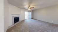 Located at 301 N Roadrunner Pkwy in Las Cruces, NM, this well-appointed 2-bedroom, 2-bathroom residence offers a comfortable and functional single-floor layout. The living room serves as the heart of the home, featuring plush carpeting, a ceiling fan, a tiled fireplace with a classic white mantle, and a set of built-in shelves ideal for display or storage. Sliding glass doors open to a private balcony, filling the space with natural light. The galley-style kitchen is thoughtfully designed with white cabinetry, light stone countertops, a stainless steel refrigerator and range, a built-in dishwasher, and light wood-look flooring that runs throughout the kitchen and entry areas. Both bedrooms are generously sized, carpeted, and feature ceiling fans with light fixtures and windows that bring in natural light. The primary bedroom includes direct access to a closet and adjoining bathroom. The bathrooms are clean and functional — one features a wide vanity with ample cabinet storage and a large mirror, while the other includes a full tub-shower combination with tiled surround. A textured ceiling is consistent throughout the home, adding a classic residential character to every room.
