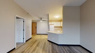 Located at 5100 S Nevada Ave in Sioux Falls, SD, this 2-bedroom, 1-bathroom unit offers a well-organized, single-floor layout designed for comfortable everyday living. The open-concept living and dining area is finished with wood-style luxury vinyl plank flooring and neutral-toned walls, creating a bright and cohesive atmosphere. A ceiling fan adds both function and style to the space, while sliding glass doors lead to a private balcony that fills the room with natural light and outdoor views. The kitchen is positioned adjacent to the living area and features white cabinetry with wood-tone accents, a double-basin sink, white appliances including a refrigerator, dishwasher, range, and microwave, and a breakfast bar peninsula that connects seamlessly to the main living space. Both bedrooms are carpeted for warmth and comfort, each equipped with a ceiling fan and window with blinds that allow for natural light and neighborhood views. The primary bedroom offers a generous footprint with ample space for furnishings. The full bathroom includes a tub/shower combination, toilet, and vanity with wood-accented cabinetry. A hallway and closet complete the layout, providing practical storage and circulation throughout the unit.
