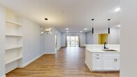 This single-floor residence showcases a thoughtfully designed open-concept layout with warm hardwood-style flooring running throughout. The expansive living and dining area is bathed in natural light from sliding glass doors that open to a private balcony, while a striking sputnik chandelier and recessed lighting add a modern, curated ambiance. Built-in shelving near the entryway provides functional display space alongside the welcoming front door.

The kitchen is a standout feature, outfitted with crisp white shaker cabinetry, marble-look quartz countertops and backsplash, stainless steel appliances including a gas range, microwave, and French door refrigerator, and a peninsula with a black and gold undermount sink. Black and gold cylindrical pendant lights complete the sophisticated aesthetic.

Two bathrooms serve the residence with distinct styles. One features a deep navy vanity with gold hardware, a backlit mirror, and a glass-enclosed shower. The second offers a white vanity, a backlit LED mirror, chrome fixtures, and a soaking tub. Both are finished with large-format tile flooring.

The bedrooms feature hardwood-style floors and contemporary light fixtures, with one bedroom benefiting from a large window offering sweeping exterior views. A generously sized walk-in closet with wrap-around hanging rods provides ample storage.