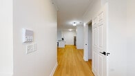 Located at 136 Lakeside Dr in St. Charles, IL, this well-appointed one-bedroom, one-bathroom unit offers a thoughtfully designed layout across a single floor. Light-toned hardwood flooring flows throughout the main living areas, complemented by crisp white walls, crown molding, and panel-style doors that give the space a clean, polished aesthetic.

The open-concept kitchen and living area serves as the heart of the home, featuring white cabinetry, stainless steel appliances including a gas range and over-the-range microwave, and a tile backsplash. The layout allows for seamless transitions between cooking and living spaces. A hallway connects the main areas to the private quarters, with convenient access to a dedicated laundry room equipped with a full-size Whirlpool washer and dryer.

The bedroom is carpeted for added comfort and is generously proportioned, featuring a sliding glass door with transom windows above that flood the room with natural light and provide views of the surrounding outdoor scenery. An attached walk-in closet with wire shelving and hanging rods offers ample storage.

The bathroom presents a refined, modern design with a white double-vanity, a large mirror, matte black hardware and fixtures, and matching hardwood-style flooring. The overall ambiance of the unit is bright, clean, and move-in ready.