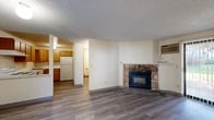 Located at 2249 S Southeast Blvd in Spokane, WA, this single-floor unit offers three bedrooms and three bathrooms within a thoughtfully arranged, compact footprint. The layout maximizes every inch of available space, making it a practical and functional residence.

The living room serves as the centerpiece of the unit, featuring a striking stone-surround fireplace with a built-in insert that adds warmth and character. Hardwood-style laminate flooring runs throughout, lending a cohesive and clean aesthetic. A sliding glass door with vertical blinds allows natural light into the living area and provides outdoor access. A wall-mounted air conditioning unit ensures year-round comfort, supplemented by baseboard heating.

The kitchen is efficiently designed in a U-shape configuration, outfitted with warm wood-toned cabinetry, white appliances including a refrigerator, dishwasher, and electric range, and a single-basin sink. The bedrooms are modestly sized with neutral walls, hardwood-style flooring, and windows offering views of surrounding greenery. The bathrooms feature wood-tone cabinetry, white countertops, and tile accents. A hallway with wood-panel doors connects the bedrooms and bathrooms, maintaining a straightforward and functional flow throughout the unit. Textured ceilings are consistent throughout the space.