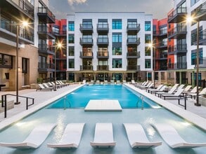 Resort-style pool courtyard with in-water loungers, sundeck seating, and private balconies surrounding the space. - Modera SoBro