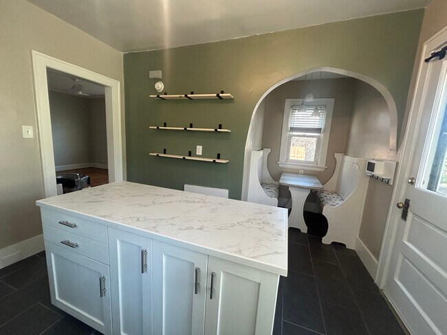 Cocina recién remodelada con electrodomésticos de acero inoxidable, isla, pisos de baldosas y rincón para desayunar. - 4524 Orkney Ave