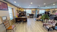 Located along Longbranch Trail in Fort Worth, TX, this single-story office space exudes a warm, Western-inspired character that reflects its Texas roots. The main workspace is open and well-lit, featuring light wood-look flooring, recessed lighting, and warm yellow walls accented with crown molding. A full-size decorative horse statue serves as a striking focal point, complemented by metal star wall art, Western-themed framed artwork, and cowhide-patterned accent chairs that reinforce the space's distinct regional identity. A large wall mirror expands the visual sense of the room, enhancing its open feel.

The primary workstation area includes a substantial dark wood desk setup with ample storage cabinetry, accommodating multiple workstations for staff. A dedicated reception or waiting area features a rustic wooden bench, wrought iron chairs, and branded signage for Chisholm Trail Town Homes, establishing the space's professional purpose.

A kitchenette with gray cabinetry and a clean countertop provides a functional break area, equipped with a coffee station and accessible storage. Natural light filters in through multiple windows fitted with blinds, keeping the interior bright and inviting. The textured ceiling and consistent flooring throughout unify the layout, creating a cohesive, comfortable, and professionally functional office environment with unmistakable Texas charm.