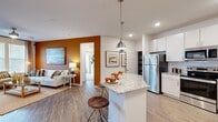 Located in Jacksonville, FL (32244), this well-appointed single-story residence offers 2 bedrooms and 3 bathrooms within a thoughtfully designed open-concept floor plan. The kitchen is a standout feature, showcasing white cabinetry, subway tile backsplash, granite countertops, stainless steel appliances, and a central island with bar seating illuminated by stylish pendant lights. It flows seamlessly into the living room, which features wood-style flooring, a bold terracotta accent wall, large windows with plantation shutters, and a ceiling fan that fills the space with natural light and warmth. The primary bedroom offers plush carpeting, natural light through oversized windows, and an accent wall that carries the home's warm color palette. Each bathroom is finished with granite countertops, tile surrounds, and wood-style flooring. Two well-organized closets provide ample storage, complemented by a dedicated laundry room with full-size washer and dryer. An attached garage with an automatic opener adds everyday convenience. The overall ambiance is modern yet warm, with consistent design details throughout creating a cohesive and inviting living environment.