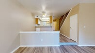 The Mariner is a thoughtfully designed two-story residence offering 2 bedrooms and 2.5 bathrooms across two well-proportioned floors. The main level features an open-concept living and dining area anchored by a tile-surround fireplace with brass accents, creating a warm and inviting atmosphere. Hardwood-style flooring flows throughout the main level, lending a clean, cohesive look. A sliding glass door opens to a private balcony with outdoor views, filling the living space with natural light. The kitchen is efficiently laid out with a peninsula breakfast bar, wood-toned upper cabinetry, granite-style countertops, white appliances including a dishwasher and refrigerator, and a window above the sink. A convenient half bathroom completes the first floor. Carpeted stairs lead to the upper level, where two generously sized bedrooms offer plush carpet flooring and ample closet space. The spacious primary bedroom benefits from a large window with views of the surrounding landscape. Both full bathrooms on the upper level are well-appointed with vanities featuring wood-trimmed cabinetry, granite-style countertops, and tub-shower combinations with wood-style flooring. The overall ambiance is comfortable, functional, and bright throughout.