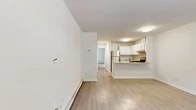 Located at 32 Nob Hill Dr in Elmsford, NY, this one-bedroom, one-bathroom residence offers a well-organized single-floor layout designed for comfortable everyday living. The open-concept living and dining area features light wood-tone flooring, neutral white walls, and natural light from a street-facing window with a wall unit for climate control and baseboard heating throughout. The space flows directly into the kitchen, which is appointed with white cabinetry, granite countertops, a stainless steel refrigerator, a gas range, and a peninsula that doubles as a breakfast bar — ideal for casual dining or additional prep space. A hallway connects the main living area to the private bedroom, which is generously proportioned and finished with soft carpet flooring, a large window overlooking greenery, and an expansive set of sliding closet doors providing substantial storage. Additional closets are accessible along the hallway, offering even more organizational capacity. The bathroom and a dedicated laundry area round out the functional layout, while a utility room adds further practicality. The overall aesthetic is clean and bright, with a consistent neutral palette throughout.