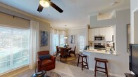 Located at 2323 Long Reach Dr in Sugar Land, TX, this single-story residence offers a thoughtfully designed open-concept floor plan that seamlessly connects the main living areas. The kitchen is a functional centerpiece, showcasing granite countertops, a curved breakfast bar with bar seating, crisp white cabinetry with ample storage, stainless steel appliances including a refrigerator, range, and microwave, and track lighting overhead. Crown molding and hardwood-style flooring add a polished touch throughout.

The dining area is highlighted by a bay window configuration wrapped in sheer white curtains, flooding the space with natural light, and anchored by a pendant light fixture above. The living room features ceiling fans, crown molding, and large windows that invite additional natural light, creating a warm and comfortable atmosphere.

Both bedrooms are carpeted and generously sized, each equipped with a ceiling fan and access to natural light through large windows with outdoor views. The primary bathroom offers a soaking tub and shower combination with marble-style tile surround and gold-tone fixtures, alongside a vanity area with granite countertops. The secondary bedroom includes convenient access to a closet and an adjoining bathroom, completing this well-appointed home.