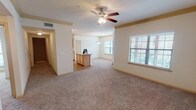 This two-floor residence offers 2 bedrooms and 2 bathrooms across a generously sized floor plan. The main living area features plush carpeting, crown molding, and a ceiling fan, with multiple windows fitted with blinds that fill the space with natural light. The open layout connects the living and dining areas seamlessly, providing a comfortable and functional flow throughout.

The kitchen is equipped with light wood cabinetry, laminate countertops, hardwood-style flooring, and white appliances including an electric range, built-in microwave, dishwasher, and refrigerator. A peninsula counter adds additional prep space and separates the kitchen from the living area. Track lighting overhead ensures the kitchen is well-lit.

The primary bathroom features a walk-in glass-enclosed shower, wood-style flooring, a single-sink vanity with light wood cabinetry, and direct access to a walk-in closet. The secondary bathroom includes a tub-shower combination with tiled accents, a vanity with matching cabinetry, and wood-style flooring.

A dedicated laundry closet houses a full-size side-by-side washer and dryer with overhead shelving for added storage. The attached garage provides a private, enclosed parking space with an automatic opener and additional storage potential.