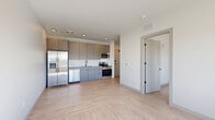This well-appointed one-bedroom, one-bathroom unit at 1851 Brevier Avenue in Cleveland's Ohio City neighborhood offers a thoughtfully designed layout across a single floor. Light hardwood-style flooring flows throughout, creating a cohesive and bright aesthetic. The open-concept kitchen and living area serves as the heart of the unit, featuring modern flat-front cabinetry in a warm taupe finish, a full suite of stainless steel appliances including a French door refrigerator with ice maker, dishwasher, gas range, and built-in microwave, all complemented by a white subway tile backsplash and ample upper and lower cabinet storage. The bedroom is a cozy, sun-filled retreat with a large window offering natural light and outdoor views. The bathroom is finished with contemporary detail, showcasing a soaking tub and shower combination with crisp white tile, a decorative terrazzo accent band, matte black fixtures, and a floating vanity with a clean white countertop. A dedicated closet provides additional storage, and a sliding-door laundry alcove houses a stacked Electrolux washer and dryer for added convenience. The unit's clean, neutral palette and modern finishes create a functional and stylish living space.