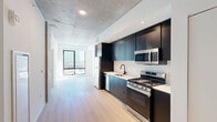 Located at 625 North 2nd Avenue in the heart of downtown Phoenix, this one-bedroom, one-bathroom unit delivers a refined industrial-modern aesthetic across a well-planned single floor. The open-concept kitchen and living area serves as the centerpiece of the home, where sleek dark cabinetry contrasts beautifully against white subway tile backsplash and light wood-tone flooring. Stainless steel appliances — including a gas range, built-in microwave, dishwasher, and full-size refrigerator — complete the chef-ready kitchen. Exposed concrete ceilings throughout lend an authentic urban character, while a large window at the end of the living area frames city views and floods the space with natural light. The bedroom continues the industrial design language with a striking exposed concrete accent wall and concrete ceiling, creating a raw yet sophisticated retreat. A dedicated closet provides practical storage. The bathroom features large-format wall tiles in the walk-in shower with a rainfall showerhead, matte black fixtures, a floating wood-toned vanity with an integrated sink, and an illuminated mirror. An in-unit laundry area adds everyday convenience. This unit offers a compelling combination of contemporary design and functional urban living in the vibrant Phoenix downtown corridor.