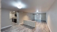 Located at 1304 Summer Oak Drive in Austin, TX, this single-story home offers a well-designed open-concept layout that seamlessly connects the main living areas. The living and dining spaces share a generous, flowing floor plan finished with light wood-style flooring throughout, creating a bright and cohesive aesthetic. A standout architectural detail is the stacked stone-accented breakfast bar that elegantly divides the kitchen from the main living area, adding texture and visual interest to the space.

The kitchen is outfitted with dark cabinetry, providing a striking contrast against the lighter tones of the surrounding space, and includes modern appliances. The open sightlines from the kitchen into the living area make the layout ideal for entertaining. Vertical blinds along the living room's rear wall filter natural light while offering privacy.

The textured ceiling adds a classic touch, while recessed lighting and ceiling fan fixtures ensure comfortable illumination throughout. The single-floor layout provides an accessible and efficient flow between rooms, with additional spaces visible toward the rear of the home. Clean white trim and neutral wall tones lend the interior a fresh, move-in-ready appearance, making this Austin home a practical and stylish choice.