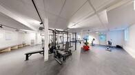 Located in Calgary, AB, this fitness centre spans a generous single floor, providing ample space for a full range of exercise activities. The facility features a clean, modern interior with white walls, a suspended tile ceiling with track lighting, and durable rubber flooring throughout — all designed to create a functional and motivating workout environment.

The strength training area is a standout feature, centered around a large multi-functional power rack system equipped with cable attachments, pull-up bars, and various weight stations. Colourful bumper plates and weight storage racks are conveniently positioned nearby, alongside adjustable benches and additional free weight equipment. A dedicated stretch and functional training zone includes resistance bands, a stability ball, a heavy bag, and adjustable incline benches, offering versatility for dynamic workouts.

The cardio section is well-appointed with multiple treadmills, an elliptical trainer, and upright and spin bikes, all positioned near windows that allow natural light to fill the space. A seating bench and water station provide a comfortable area for rest between sessions. The layout is thoughtfully organized to maximize floor space and ensure smooth circulation throughout the facility, making it a comprehensive fitness destination suitable for a wide range of training goals.