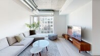 Located on the seventh floor at 748 Bathurst Street in Toronto's vibrant Annex neighbourhood, this two-bedroom, two-bathroom unit offers a thoughtfully designed layout across a single floor. The space features a distinctive industrial-loft aesthetic, defined by exposed concrete ceilings and visible ductwork that lend architectural character throughout.

The open living and dining area is bathed in natural light from large floor-to-ceiling windows that frame views of the surrounding cityscape. Light wood flooring runs continuously through the main living spaces, enhancing the bright, airy atmosphere. The dining area comfortably accommodates a full-sized table and connects seamlessly to the living space, creating a cohesive area for entertaining.

The primary bedroom features a sliding glass partition that opens to the living area, maintaining connectivity while offering privacy. Exposed ductwork continues here, reinforcing the loft aesthetic. The second bedroom is equally well-appointed with concrete ceiling details and natural light.

Both bathrooms include full soaker tub-shower combinations finished in clean white tile. A private balcony accessible from the living area provides outdoor space with open urban views, completing this well-rounded urban residence.