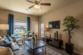 Located in Spring Branch, TX, this thoughtfully designed one-bedroom unit offers a cohesive blend of modern finishes and comfortable living across a single floor. The living area is bright and welcoming, featuring wood-look plank flooring, a ceiling fan, and multiple windows dressed with rich blue drape panels that allow generous natural light while adding a stylish accent. A neutral color palette anchors the space, complemented by a bold accent wall that adds depth and visual interest.

The kitchen is a standout, showcasing dark espresso cabinetry, granite-style countertops, a mosaic tile backsplash, and a peninsula that provides additional prep and serving space. Recessed lighting and black appliances complete the sleek, functional aesthetic.

The bedroom is a calm retreat with plush carpeting, ample storage, and access to the en-suite bathroom. The bathroom features a granite-topped vanity with dark cabinetry, a large mirror, and clean, classic fixtures.

Throughout the unit, the design maintains a consistent and polished look, with warm beige tones, dark wood furniture accents, and coordinated blue décor tying each room together into a cohesive and inviting home.