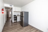 This single-floor unit offers a straightforward, efficiently designed layout with a clean, modern aesthetic throughout. Light wood-style laminate flooring runs continuously across all areas, providing a cohesive and easy-to-maintain surface that brightens the interior.

The kitchen is compact yet functional, featuring white shaker-style upper and lower cabinetry, a stainless steel gas range, a full-size stainless steel refrigerator, and a single-basin sink with a granite-style countertop. A textured ceiling and overhead ventilation are present throughout the unit.

The living and entry areas are open and simply appointed, with white walls offering a neutral backdrop. A window in the entry area allows natural light to filter in, while a dedicated entry door provides direct access. Additional rooms along the hallway offer versatile use of space, each featuring the same light flooring and white walls.

The bathroom includes a full tub and shower combination with a white surround, a toilet, and a vanity with sink. The clean, all-white finish maintains consistency with the rest of the unit's understated palette.

Overall, the unit presents a freshly updated, move-in-ready environment with a minimalist design that emphasizes functionality and simplicity.