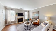 Located at 330 Stone Falls Dr in Ada, Michigan, this single-floor residence offers a thoughtfully designed layout with a warm, contemporary aesthetic throughout. The living room serves as the heart of the home, highlighted by a tile-surround fireplace with a classic white mantle, hardwood flooring, crown molding, and multiple windows that draw in generous natural light. Track lighting and a large statement canvas add both function and character to the space.

The kitchen is well-equipped with rich dark cabinetry, granite countertops, stainless steel appliances, a subway tile backsplash, and a double basin sink. A door from the kitchen provides convenient outdoor access. Adjacent to the kitchen, the dining area occupies a charming bay-windowed nook, bathed in natural light and anchored by an elegant pendant chandelier.

The primary bedroom features a distinctive bay window configuration, plush carpeting, and rich wood furnishings, creating a serene retreat. A second bedroom offers soft neutral tones, carpeted flooring, and ample natural light through sheer-curtained windows. Two bathrooms serve the residence, each featuring dark wood vanities with white countertops and hardwood-style flooring, with one bathroom including a shower-tub combination. The overall ambiance is cohesive, modern, and inviting.