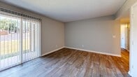Located at 2112 Oak Tree Villa Dr in Hopkinsville, Kentucky, this two-bedroom, two-bathroom single-floor home offers a practical and comfortable layout with clean, neutral finishes throughout. The living room serves as the heart of the home, featuring wood-look plank flooring, a textured ceiling, and a sliding glass door with vertical blinds that allows natural light to fill the space. The kitchen is well-appointed with dark brown cabinetry offering ample storage, white appliances including a range and refrigerator, a double sink, and light wood-look flooring that ties seamlessly to the living area. Both bedrooms are finished with plush carpet and neutral gray walls, creating a calm and restful atmosphere. The primary bedroom is generously sized and connects to a hallway leading to additional rooms. The second bedroom features a window with natural light and outdoor views. The two bathrooms are functional and simply designed — one features a white vanity with a mirrored medicine cabinet and wood-look flooring, while the second offers similar fixtures with a warm wood-framed mirror. Clean white trim and consistent neutral tones throughout the home contribute to a cohesive, move-in-ready aesthetic.