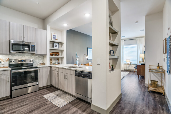 Gray finish package kitchen, living, and dining area with hard surface flooring throughout - Avalon West Plano