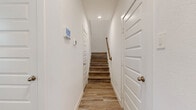 This two-story home offers a thoughtfully planned layout across two floors, providing ample space for comfortable living. The main level features an open-concept kitchen and living area, where the kitchen stands out with crisp white shaker cabinetry, granite countertops, a central island with an undermount sink, and stainless steel appliances. Wood-look plank flooring flows consistently throughout, lending a clean and cohesive aesthetic to every room.

The upper level hosts the majority of the bedrooms, connected by a hallway and accessible via a staircase with a warm wood-toned handrail. The primary bedroom offers a generous footprint with its own dedicated bathroom featuring a wide vanity with white cabinetry and built-in shelving, complemented by a spacious walk-in closet with multi-rod hanging storage. The three additional bedrooms are bright and well-proportioned, each finished with the same wood-look flooring and ceiling fans with natural light provided through windows. A dedicated laundry room with a full-size washer and dryer adds further convenience. Throughout the home, recessed lighting, white panel doors, and a neutral color palette create a modern, move-in-ready environment.