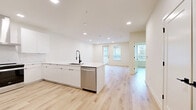 This modern home in Round Rock, TX offers a thoughtfully designed open-concept layout with clean lines and contemporary finishes throughout. Light wood-look flooring flows seamlessly across the entire space, complementing the crisp white walls and recessed lighting that create a bright, airy ambiance.

The kitchen is a standout feature, anchored by a large peninsula with a white quartz countertop and a black matte faucet with an undermount sink. Stainless steel appliances include a Whirlpool range with a sleek hood vent and a French door refrigerator, while white cabinetry with matte black hardware and a marble-look tile backsplash complete the polished look. The kitchen opens directly into the living area, which receives natural light from multiple windows and a glass door leading to an outdoor area.

The bedroom is a comfortable retreat with windows that bring in natural light and views of the surrounding neighborhood. The full bathroom impresses with its elongated double-vanity featuring white cabinetry, black hardware, and lighted mirrors, alongside a frameless glass walk-in shower with large-format tile. The overall design of this home is clean, modern, and move-in ready.