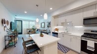 Located at 1625 Santa Venetia St in Chula Vista, CA, this single-floor residence offers a thoughtfully designed open-concept layout that seamlessly connects the kitchen, dining, and living areas. The kitchen is a standout feature, outfitted with sleek white cabinetry, a white subway tile backsplash, quartz countertops, and a full suite of stainless steel appliances including a gas range, over-the-range microwave, dishwasher, and refrigerator. A central island with pendant lighting overhead provides additional prep space and casual seating. Light wood-style flooring runs throughout the main living areas, enhancing the bright and airy atmosphere. The living room is generously sized, bathed in natural light from large windows and a glass-paneled entry door, creating a welcoming and open ambiance. The bedroom features plush carpeting, a large window with blinds and curtains, and a comfortable, serene atmosphere ideal for rest. The bathroom is clean and modern, featuring light wood cabinetry, a white countertop vanity, a large mirror, and well-organized storage. Throughout the residence, recessed lighting and neutral wall tones contribute to a cohesive, contemporary aesthetic that is both functional and inviting.