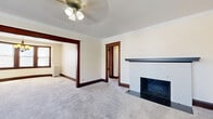 Located at 2125 E Kenwood Blvd in Milwaukee's desirable East Side neighborhood, this single-floor, 3-bedroom, 1-bathroom home showcases classic architectural character throughout. Rich dark wood trim, crown molding, and paneled doors lend a timeless quality to every room.

The living area is anchored by a decorative tiled fireplace with a dark mantel and flows seamlessly through a wide, wood-framed archway into the dining room. The dining room is highlighted by a curved bay window with multiple panes that floods the space with natural light, complemented by a warm chandelier overhead and a vintage radiator below.

The kitchen features white cabinetry, dark granite-style countertops, a gas range, tile flooring, and a convenient built-in pantry with open shelving. The bathroom offers a classic white subway tile surround and a full soaking tub with a window above for natural light.

All three bedrooms are carpeted and generously proportioned, with the spacious primary bedroom featuring a ceiling fan, built-in closets with original wood doors, crown molding, and a radiator. Additional bedrooms include large windows, radiator heating, and original woodwork details. One bedroom retains a charming wall-mounted sink. Throughout the home, carpet, dark baseboards, and vintage fixtures create a cohesive, character-rich ambiance.