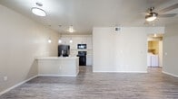 This well-designed one-bedroom, two-bathroom unit in Tucson, AZ offers a thoughtful layout that maximizes every square foot. The open-concept kitchen and living area serves as the heart of the space, featuring wood-look flooring, neutral-toned walls, and a ceiling fan that enhances airflow. The kitchen is appointed with white cabinetry, stone-look countertops, a peninsula island with a double basin sink, pendant lighting, and black appliances including a range, microwave, refrigerator, and dishwasher. Sliding glass doors in the living area open to a private patio, bringing in natural light and outdoor access. The bedroom is a comfortable size, offering a dedicated closet with built-in shelving and hanging rods, alongside convenient access to an in-unit laundry closet housing a full-size washer and dryer. Two bathrooms serve the unit, each featuring a tub-shower combination, vanity with storage, and wood-look flooring. The consistent use of light, neutral finishes and hard-surface flooring throughout gives the space a clean, cohesive aesthetic well-suited to Tucson living.
