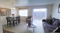Located at 552 Springridge Rd in Clinton, Mississippi, this two-floor residence offers a comfortable and functional layout designed for everyday living. The main living area is bright and welcoming, featuring plush wall-to-wall carpeting that adds warmth underfoot. Large windows dressed with decorative valances allow generous natural light to fill the space, creating an airy and open atmosphere. A full-width sliding glass door provides seamless access to an outdoor patio area, where additional seating can be enjoyed, further extending the living space outdoors. The living room comfortably accommodates a sofa and accent chair arrangement centered around a circular coffee table, making it an ideal setting for relaxing or entertaining. Adjacent to the living area, a dedicated dining space features a dark-toned dining set beneath a classic chandelier, providing a defined area for meals. The neutral color palette throughout — featuring soft beige walls and light ceilings with a textured finish — lends a clean, cohesive look that complements a variety of décor styles. Spanning two floors, the home offers ample space for both living and private quarters, providing a well-rounded residential experience in the Clinton, Mississippi area.