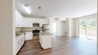 This 2-bedroom, 3-bathroom residence delivers a practical and polished single-floor layout designed for comfortable everyday living. The kitchen serves as the centerpiece of the home, featuring crisp white shaker cabinetry, granite countertops, a central island, and a full suite of stainless steel appliances including a gas range, microwave, and refrigerator. Rich hardwood-style flooring runs throughout the kitchen and main living areas, lending warmth and continuity to the open layout.

Both bedrooms are carpeted and bathed in natural light from large windows that offer views of surrounding greenery. The generously sized primary bedroom includes dedicated closet space outfitted with wire shelving systems for organized storage. A second closet provides additional storage capacity elsewhere in the home.

The three bathrooms are finished with neutral tile flooring and white vanities. One bathroom features a full soaking tub with a curved shower rod, while another includes a wide vanity with a large mirror and bright overhead lighting.

A standout feature of this residence is the private outdoor patio, enclosed by an iron gate and low stone walls, surrounded by mature trees and landscaped plantings — ideal for outdoor relaxation. The multi-story building exterior showcases a contemporary design with horizontal siding, balconies, and well-maintained communal grounds.