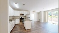 This 2-bedroom, 3-bathroom residence delivers a practical and polished single-floor layout designed for comfortable everyday living. The kitchen serves as the centerpiece of the home, featuring crisp white shaker cabinetry, granite countertops, a central island, and a full suite of stainless steel appliances including a gas range, microwave, and refrigerator. Rich hardwood-style flooring runs throughout the kitchen and main living areas, lending warmth and continuity to the open layout.

Both bedrooms are carpeted and bathed in natural light from large windows that offer views of surrounding greenery. The generously sized primary bedroom includes dedicated closet space outfitted with wire shelving systems for organized storage. A second closet provides additional storage capacity elsewhere in the home.

The three bathrooms are finished with neutral tile flooring and white vanities. One bathroom features a full soaking tub with a curved shower rod, while another includes a wide vanity with a large mirror and bright overhead lighting.

A standout feature of this residence is the private outdoor patio, enclosed by an iron gate and low stone walls, surrounded by mature trees and landscaped plantings — ideal for outdoor relaxation. The multi-story building exterior showcases a contemporary design with horizontal siding, balconies, and well-maintained communal grounds.