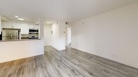 This 350 square foot studio apartment in Los Angeles offers a thoughtful blend of modern amenities and efficient design. The open-concept layout seamlessly integrates the living area, kitchen, and sleeping space, creating a sense of spaciousness within the compact footprint.

The kitchen showcases sleek white cabinetry, contrasting with black appliances, including a full-sized refrigerator. Stainless steel accents and a contemporary faucet add a touch of sophistication. The galley-style layout maximizes functionality in the limited space.

The living area features a fireplace, adding warmth and character to the room. A large sliding glass door floods the space with natural light and provides access to an outdoor area, expanding the living space and creating an indoor-outdoor flow.

The bathroom, while compact, is well-appointed with a vanity, toilet, and a shower/tub combination. A white shower curtain and light-colored walls contribute to a clean, fresh aesthetic.

Throughout the apartment, grey wood-look flooring unifies the space and adds a modern, neutral backdrop. The walls are painted in a light color, further enhancing the sense of openness and brightness.

Storage solutions are integrated throughout, including kitchen cabinetry and a closet, addressing the needs of urban living in a limited square footage. The overall design emphasizes functionality and style, creating a comfortable living environment in a prime Los Angeles location.