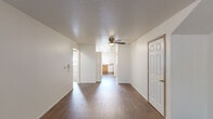 Located in Portland, Oregon, this single-floor, two-bedroom, two-bathroom unit offers a practical and comfortable layout. The combined living and dining area is bright and open, featuring durable hardwood-style flooring and a ceiling fan, with sightlines connecting directly to the kitchen. The kitchen is well-appointed with warm oak cabinetry, laminate countertops, and white appliances including a refrigerator, dishwasher, and electric range. A window above the sink allows natural light to fill the space. The two bedrooms are carpeted for comfort; the primary bedroom offers generous proportions, a sliding-door closet, and its own dedicated access. The second bedroom is also bright, featuring a large window with vertical blinds. Two full bathrooms serve the unit — one includes a shower stall with sliding glass doors, while the other provides a vanity with wood cabinetry and hardwood-style flooring in both. A dedicated laundry room houses a full-size washer and dryer with overhead shelving. Throughout the unit, four closets provide exceptional storage. Textured ceilings are present in the common areas, adding a classic finishing touch to this well-organized and functional home.
