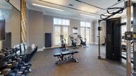 Located at 5426 Main St in Spring Hill, TN, this single-floor fitness center is a comprehensively outfitted facility designed to support a wide range of workout routines. The space features durable rubber flooring throughout, providing a safe and functional surface for all types of exercise.

The cardio zone is anchored by a row of large windows that flood the area with natural light and offer outdoor views, creating an energizing atmosphere. TRUE-brand treadmills and elliptical machines are positioned to take full advantage of this bright setting. Nearby, a dedicated cycling area houses multiple stationary bikes equipped with individual screens, ideal for immersive ride sessions.

The strength and functional training area is defined by floor-to-ceiling mirrors that visually expand the space, complemented by decorative textured accent panels that add a modern aesthetic. This zone includes a full dumbbell rack, a weight bench, a heavy bag for boxing training, medicine balls, and a TRUE cable machine system. A large mounted flat-screen TV enhances the workout environment.

Ceiling fans and linear LED lighting fixtures are installed throughout, ensuring the space remains comfortable and well-lit. The overall design balances contemporary style with practical functionality, making this fitness center a standout amenity for the Spring Hill community.