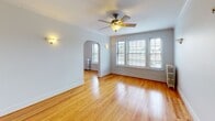 Located at 622 Harrison St in Oak Park, IL, this single-floor space showcases classic architectural character throughout. Gleaming hardwood floors run continuously across the living areas, complemented by crisp white walls, substantial crown molding, and traditional baseboard trim that speak to the building's timeless design. The spacious living room draws immediate attention with its elegant arched doorway, ceiling fan, wall sconces, and a generous bank of windows fitted with blinds that allow abundant natural light while maintaining privacy. A cast-iron radiator adds to the period charm. The adjoining dining area features a chandelier and its own radiator, creating an inviting atmosphere. The bedrooms continue the hardwood flooring and offer ceiling fans, wall sconces, and bright windows with views of the surrounding greenery. The kitchen is well-equipped with white cabinetry, grey stone countertops, tile backsplash, stainless steel appliances, and a back door that lets in additional natural light. The bathroom is cleanly finished in white tile, featuring a tub-shower combination and a radiator, with a frosted window for privacy. Throughout, the space maintains a cohesive, classic aesthetic rooted in early 20th-century Oak Park architecture.