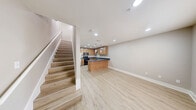 Located at 711 W 32nd St in Austin, TX, this two-floor residence offers a practical and well-appointed layout spread across two levels. Light wood-style flooring runs throughout, creating a cohesive and clean aesthetic from room to room.

The main level houses the kitchen and living area. The kitchen is generously equipped with warm wood cabinetry, dark countertops, recessed and pendant lighting, a stainless steel refrigerator, a black dishwasher, and a range — all arranged around an L-shaped counter with a peninsula that opens to the adjacent living space.

Two bathrooms serve the home, with at least one featuring a full soaking tub set within floor-to-ceiling tile surround, complemented by wood-toned cabinetry and a dark countertop vanity.

The upper level hosts the bedroom, which benefits from multiple windows that bring in natural light and are fitted with horizontal blinds for privacy. A ceiling fan adds both comfort and style to the space. The hallway and closet on this level provide practical storage and circulation.

A staircase connects the two floors, as clearly visible in the dollhouse view of the layout. Neutral gray-toned walls throughout contribute to the space's clean, modern feel, making it a functional and comfortable home in the heart of Austin.