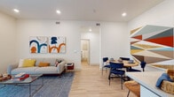 This thoughtfully designed single-floor unit offers a bright and contemporary living experience with a cohesive aesthetic carried throughout. The open-concept living and dining area serves as the heart of the space, featuring light hardwood flooring, recessed lighting, and crisp white walls that create an airy, welcoming atmosphere. Large sliding glass doors in the living area flood the space with natural light and provide access to an outdoor area. The dining space comfortably accommodates a round wooden table paired with navy upholstered chairs, flowing seamlessly into the living room.

The kitchen is outfitted with gray shaker-style cabinetry, white quartz countertops, a classic white tile backsplash, and stainless steel appliances, offering both style and functionality. Two bedrooms provide comfortable retreats; the primary bedroom features plush carpeting, generous ceiling height, and a walk-in closet, while the second bedroom benefits from a large window with ample natural light. Two bathrooms serve the unit — one featuring a vanity with sage-green cabinetry and a framed mirror, and the other a full tub-shower combination with warm wood-tone flooring. A smart thermostat and modern fixtures complete this well-finished space.