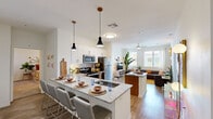 Located at 1100 East Apache Boulevard in Tempe, Arizona, this single-floor residence offers four bedrooms and three bathrooms thoughtfully arranged for comfortable living. The open-concept kitchen and living room serve as the heart of the home, featuring granite countertops, a large island with bar seating, stainless steel appliances, white cabinetry with warm wood accents, and stylish pendant lighting. Wood-style flooring flows through the main living area, which is bathed in natural light from oversized windows. The spacious living room comfortably accommodates a full seating arrangement and benefits from a ceiling fan and views of the surrounding neighborhood. Each bedroom is carpeted and well-proportioned, with large windows that invite natural light. The primary bedroom includes access to a walk-in closet with built-in shelving and hanging rods. The bathrooms are finished with granite-topped vanities and warm wood cabinetry, with tub-shower combinations featured in the secondary baths. Three dedicated closets provide ample storage throughout the unit. A connecting hallway links the private bedroom wing to the main living spaces, creating a practical and well-organized floor plan suited for shared or family living.