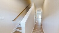 Located at 2005 Waterside Dr in Suffolk, VA, this two-story home offers a thoughtfully organized layout spread across two floors. Light-toned hardwood flooring flows consistently throughout the living areas, bedrooms, and hallways, creating a cohesive and clean aesthetic.

The main floor houses the kitchen and living room, which opens to the outdoors via a sliding glass door that brings in abundant natural light and views of the surrounding exterior. The kitchen is outfitted with white shaker-style cabinetry, granite countertops, stainless steel appliances including a refrigerator and range, and recessed lighting overhead. An attached garage with drywall-finished walls and a concrete floor provides direct interior access.

Upstairs, a bright hallway connects the two bedrooms and bathrooms. The spacious primary bedroom features light hardwood floors, a ceiling fan, and direct access to a private en-suite bathroom complete with a granite-topped vanity, white cabinetry, and a glass-enclosed shower. The second bedroom is equally well-appointed with hardwood floors and a ceiling fan. Three full bathrooms serve the home, including one on the main level with a tub-shower combination and brushed nickel fixtures. A dedicated closet adds practical storage to the upper level.