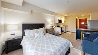 Located at 2752 NE Hogan Dr in Gresham, Oregon, this efficiently designed studio unit offers a thoughtfully arranged single-floor layout that maximizes every square foot. The open-concept living area seamlessly integrates the kitchen, dining, and sleeping spaces into one cohesive room, creating a functional and comfortable environment. The kitchen is equipped with stainless steel appliances, including a refrigerator, range, dishwasher, and microwave, complemented by white cabinetry and a clean countertop workspace. Light wood-style flooring runs throughout the main living area, enhancing the bright and airy ambiance. A large window in the sleeping area allows natural light to fill the room while offering views of the surrounding neighborhood. Track lighting provides additional illumination across the open space. The unit features two bathrooms: one with a vanity area featuring a wide mirror, white cabinetry, and grey countertops, and a second full bathroom with a shower/tub combination and tile flooring. The entryway includes a coat rack and storage shelf, providing practical organization near the richly toned front door. Overall, the unit presents a clean, modern aesthetic suited for efficient, comfortable living.