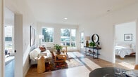 Located at 7900 SE Luther Rd in Portland, Oregon, this single-floor residence offers a thoughtfully designed open-concept layout with clean, modern finishes throughout. The bright living room is bathed in natural light from large windows that frame outdoor views of surrounding greenery, with light hardwood-style flooring extending seamlessly across the space.

The kitchen serves as a central hub, featuring a generous island with a white quartz countertop, gray shaker-style cabinetry, a matte black faucet, stainless steel appliances, and striking black pendant lights overhead. A dedicated dining area sits adjacent, offering a natural transition between cooking and gathering spaces.

The bedrooms are well-proportioned and serene, each benefiting from ample natural light through well-placed windows. The primary bathroom includes a dual-sink vanity with a white quartz countertop, deep navy cabinetry, and large mirrors illuminated by modern sconce lighting. A secondary bathroom offers a full soaking tub and shower combination with clean white finishes and hardwood-style flooring.

Throughout the residence, the design palette of crisp white walls, light flooring, and dark accent fixtures creates a cohesive, contemporary aesthetic. The overall ambiance is bright, welcoming, and functional, making it a well-balanced modern living space in Southeast Portland.