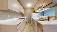 This single-floor, 2-bedroom, 1-bathroom unit in Inkster, Michigan offers a functional and straightforward layout across a comfortable footprint. The open living and dining area is finished with plush gray carpet and warm neutral-toned walls, creating a cohesive, inviting atmosphere. A pass-through window connects the living area to the kitchen, enhancing the sense of openness. A ceiling fan adds comfort to the main living space. The galley-style kitchen is efficiently designed with light wood cabinetry, white laminate countertops, tile flooring, and a full suite of white appliances, including a refrigerator, electric range, and dishwasher. A ventilation hood is positioned above the range for added functionality. Both bedrooms are carpeted, featuring the same warm neutral palette, baseboard heating units, and ample natural light. One bedroom includes a sliding glass door that opens to an outdoor view, while the other features a closet for convenient storage. The full bathroom is finished with tile flooring and includes a vanity with a sink, a mirror, and a shower-tub combination. Baseboard heating is present throughout the unit, ensuring consistent warmth. The layout offers a practical and comfortable living environment suited for everyday residential use.