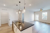 Located at 1000 Jasper Ln in Saint Peters, MO, this thoughtfully designed one-bedroom, one-bathroom unit offers a modern aesthetic throughout its efficiently laid-out single floor. The open-concept kitchen and living area serves as the heart of the home, anchored by a central island with a striking dark quartz countertop, undermount sink, and a trio of stylish pendant lights overhead. White shaker-style cabinetry, stainless steel appliances, and a smooth tile backsplash complete the kitchen. Light wood-look flooring flows throughout the main living areas, enhancing the bright, clean atmosphere created by white walls and recessed lighting. The living area benefits from a ceiling fan and direct access to the outdoors through a glass-panel door flanked by windows. The bedroom is carpeted for comfort, features a ceiling fan, a window with outdoor views, and leads to a spacious walk-in closet with built-in shelving. The full bathroom is finished with a granite-topped vanity, white cabinetry, and a tub-shower combination. A dedicated laundry area houses a full-size washer and dryer with overhead wire shelving. Two additional closets and a utility room provide ample storage throughout the unit.