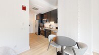 Located at 1151 4th St SW in Washington, DC's Southwest Waterfront neighborhood, this thoughtfully designed studio offers a smart, efficient layout that maximizes every square foot. The open-plan living area features light wood flooring, clean white walls, and large windows that bring in natural light, creating a bright and welcoming ambiance.

The kitchen is well-appointed with dark cabinetry extending to the ceiling for ample storage, stainless steel appliances including a refrigerator, electric range, built-in microwave, and dishwasher, complemented by granite countertops and a classic white subway tile backsplash. A compact dining area adjacent to the kitchen provides a practical space for everyday meals.

The bathroom is finished with large-format light tile flooring, white subway tile surrounding a full bathtub and shower combination, and a clean, minimalist aesthetic throughout. A dedicated in-unit laundry area houses a stacked Bosch washer and dryer, adding a significant convenience rarely found in compact urban residences.

The living space is accented with tasteful design touches, including contemporary artwork and thoughtfully placed lighting, contributing to an overall modern and polished feel. This space is ideally suited for individuals seeking a well-equipped, low-maintenance home in the heart of Washington, DC.