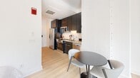 Located at 1151 4th St SW in Washington, DC's Southwest Waterfront neighborhood, this thoughtfully designed studio offers a smart, efficient layout that maximizes every square foot. The open-plan living area features light wood flooring, clean white walls, and large windows that bring in natural light, creating a bright and welcoming ambiance.

The kitchen is well-appointed with dark cabinetry extending to the ceiling for ample storage, stainless steel appliances including a refrigerator, electric range, built-in microwave, and dishwasher, complemented by granite countertops and a classic white subway tile backsplash. A compact dining area adjacent to the kitchen provides a practical space for everyday meals.

The bathroom is finished with large-format light tile flooring, white subway tile surrounding a full bathtub and shower combination, and a clean, minimalist aesthetic throughout. A dedicated in-unit laundry area houses a stacked Bosch washer and dryer, adding a significant convenience rarely found in compact urban residences.

The living space is accented with tasteful design touches, including contemporary artwork and thoughtfully placed lighting, contributing to an overall modern and polished feel. This space is ideally suited for individuals seeking a well-equipped, low-maintenance home in the heart of Washington, DC.