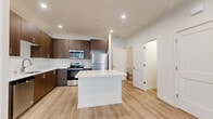 Located at 8969 N Cottonwood St in Camas, WA, this contemporary two-story home offers 3 bedrooms and 5 bathrooms thoughtfully distributed across two levels. The main floor features an open-concept layout where the kitchen and living room flow seamlessly together, creating a bright and welcoming communal space. Light wood-tone flooring extends throughout the main level, complementing the clean white walls and recessed lighting overhead. A standout feature of the living area is a full-height tile-surround linear fireplace, providing a bold modern focal point. The kitchen is well-appointed with rich dark wood cabinetry, crisp white quartz countertops, a central island, and a full suite of stainless steel appliances including a dishwasher, range, microwave, and refrigerator. A convenient bathroom is also located on the main floor. Upstairs, three bedrooms are finished with plush carpeting and feature windows that bring in natural light, along with closet space. The upper level hosts the remaining bathrooms, including tub-shower combinations with brushed nickel fixtures, as well as a dedicated laundry room with a washer and dryer. The home's clean, modern aesthetic is consistent throughout, offering a polished and functional living environment.