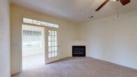 Located at 5124 Southwind Rd in Greensboro, NC, this single-story home offers a well-designed layout with a variety of comfortable living spaces. The spacious living room is a central highlight, featuring a corner fireplace, plush carpeting, a ceiling fan, and a set of French doors topped with transom windows that invite abundant natural light and provide access to the outdoors. Adjacent to the living area, a dedicated room impresses with tall arched windows that frame views of the surrounding greenery, creating a bright and airy atmosphere. The kitchen is outfitted with white cabinetry, granite-look countertops, stainless steel appliances including a refrigerator, dishwasher, microwave, and range, all complemented by warm hardwood-style flooring. The bedrooms are carpeted and generously sized, offering ample closet space and a calm, neutral palette. The bathroom features white cabinetry with under-sink storage, a large vanity mirror, hardwood-style flooring, and a tub-shower combination. Throughout the home, cream-toned walls and consistent finishes create a cohesive and inviting ambiance suited for comfortable everyday living.